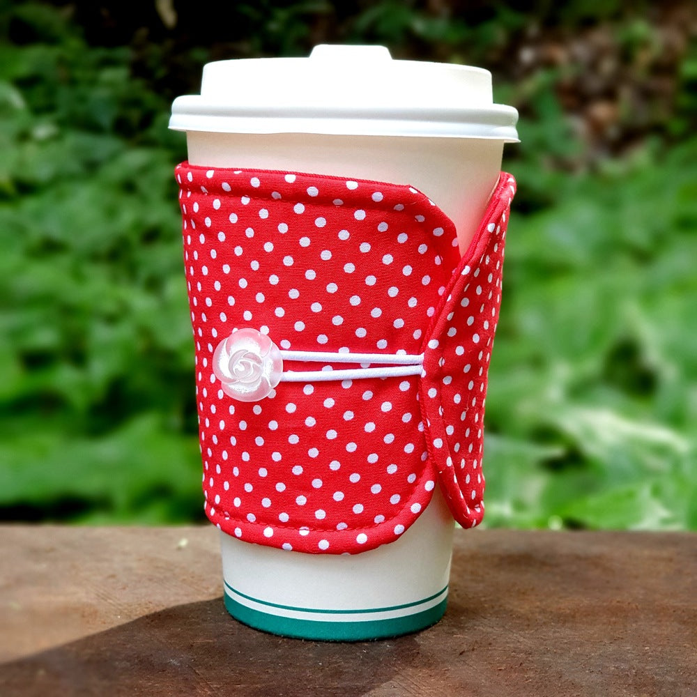 A bright red fabric cup cosy wth white polka dots and carved rose button detail by Birdy & The Boys