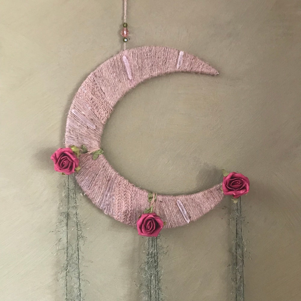 A hand-woven moon-shaped dreamcatcher in pink by Chex Creatrix Art