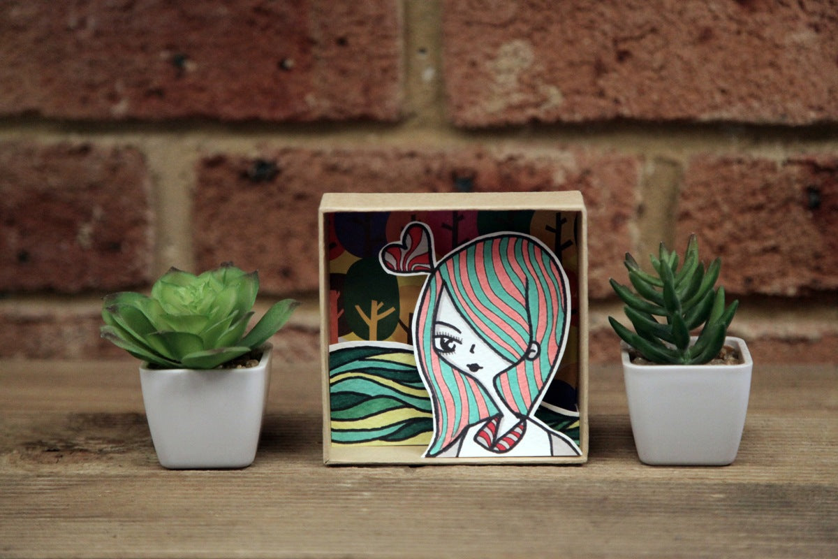 A handmade cardboard shadow box with layered illustrations by dentanARTS