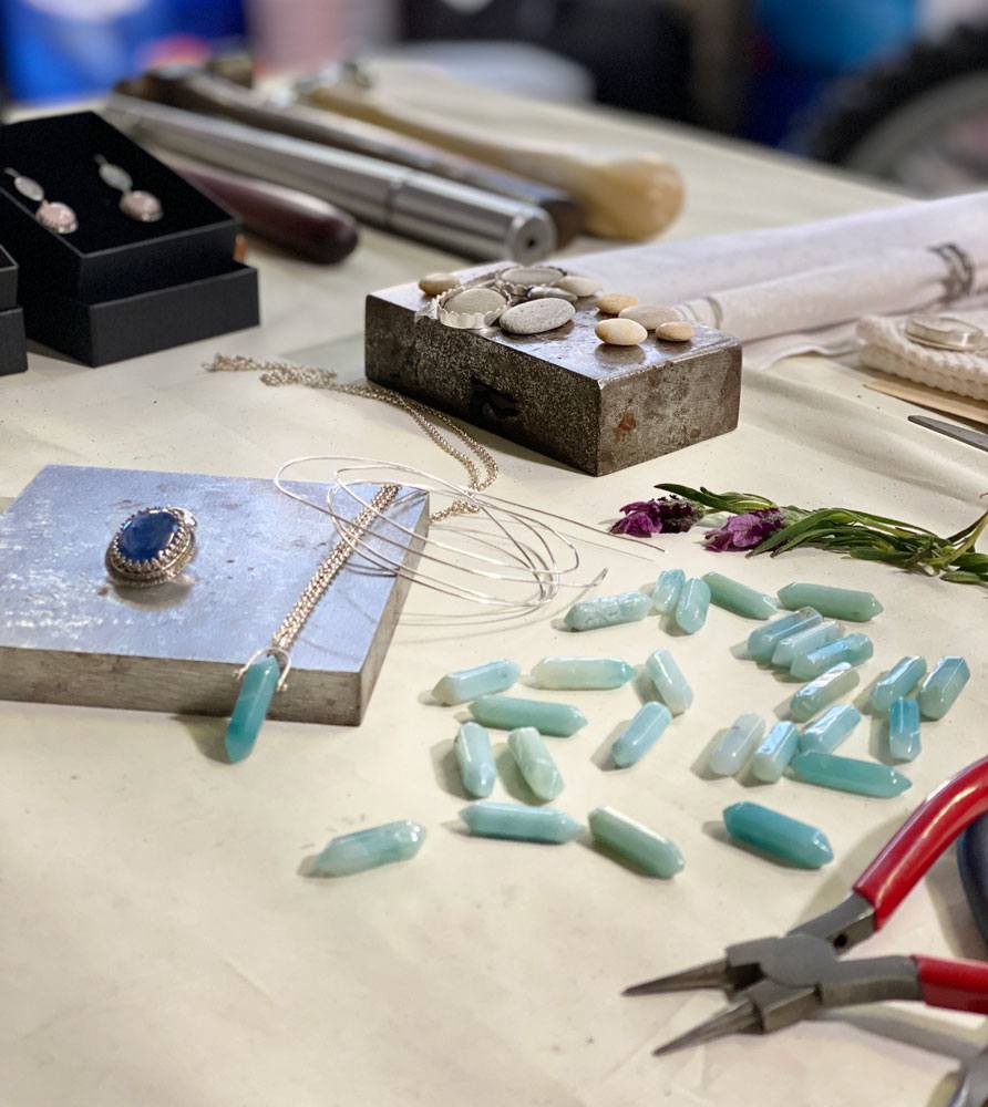 An assortment of tools, crystals, jewellery wire, stones, and settings in progress on JennyÕs workshop table