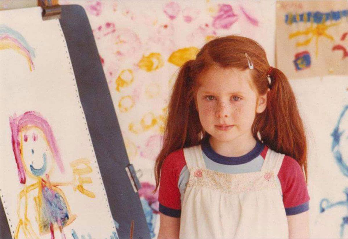 Sally Dixon as a young girl with some of her early paintings in the background