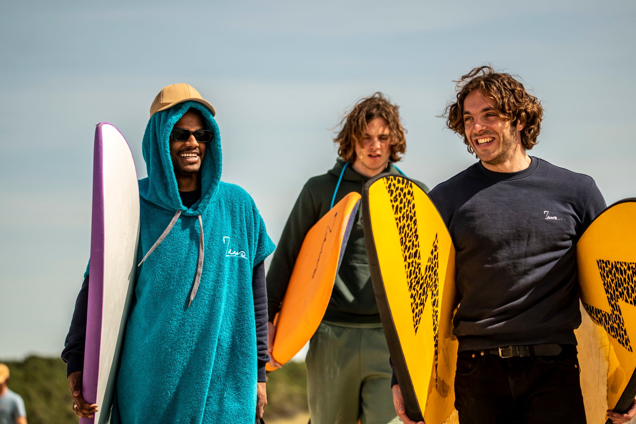 Un grupo de surfistas cargando sus tablas de surf.