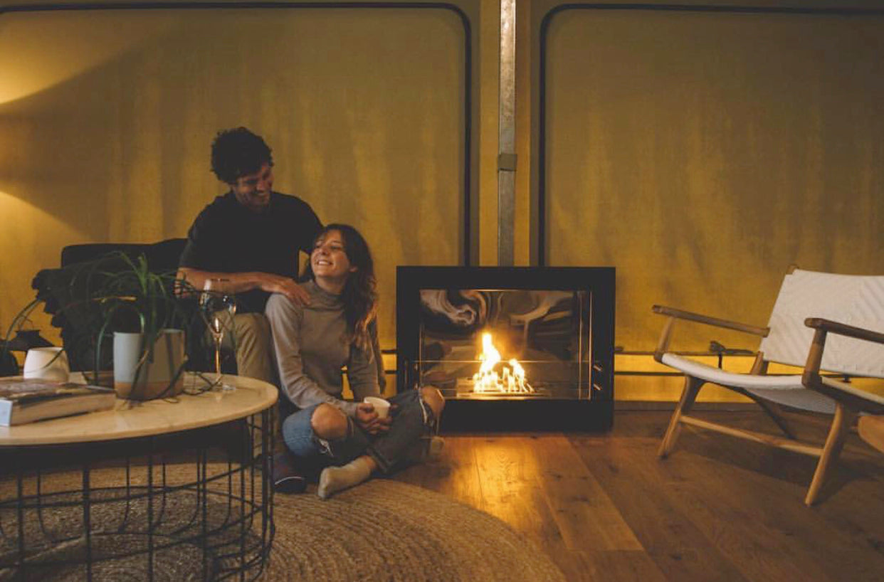 A couple sitting beside a fireplace