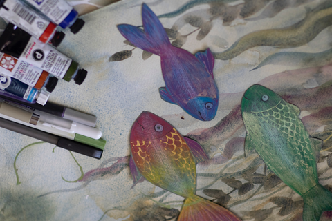 mixed media three colorful fish artwork with materials laid out