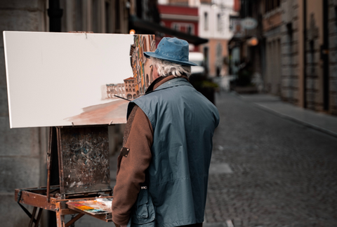 an artist works on a painting from observation on a city street corner