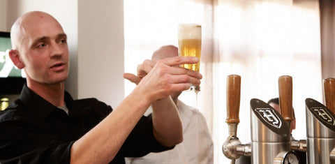 Man controleert glas bier met schuimkraag op kwaliteit