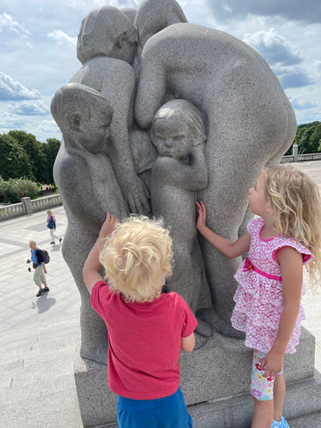 small kids with a vigeland statue of children