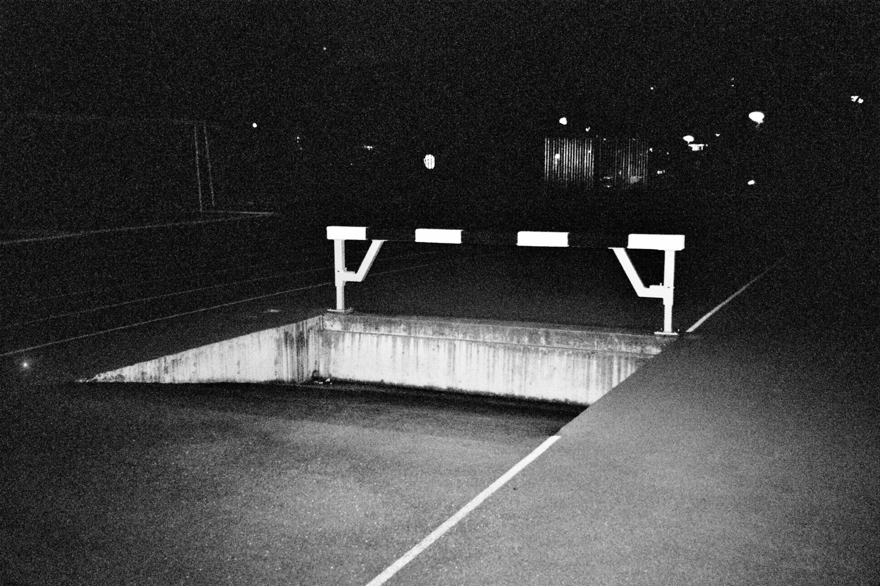 Black and white photograph of an empty steeplechase at night.