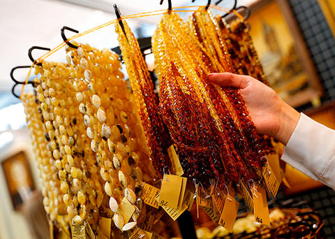 A display stand showcasing strands of Lithuanian amber necklaces in various designs.