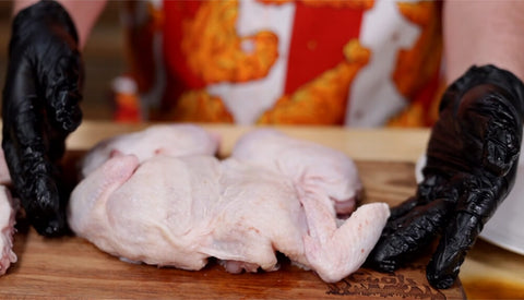 This image shows Scott spatchcocking the chicken in preparation for peri peri chicken on a rotisserie