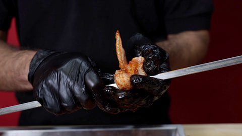 This image shows chicken wings being thread in the skewer