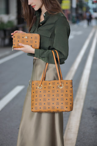 امرأة شابة تبتسم حاملة حقيبة يد بنية كبيرة مزينة بنقوش مربعات وحروف متشابكة، مع خلفية طريق المدينة