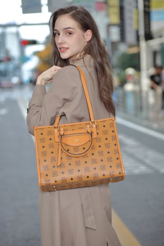 A luxurious women's Saga leather handbag in light brown, carried by a model on her shoulder in the city