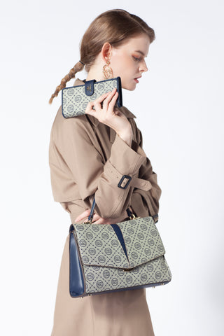 A woman in a beige coat holds a small purse matching the handbag in a light gray and blue design.