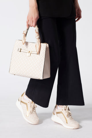 Woman wearing a black coat and carrying a classic beige women's handbag with a gold buckle