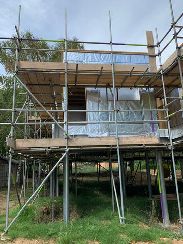 The exterior of the build, scaffold surrounds the frame with insulation visible