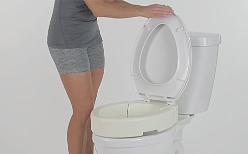 woman lifting lid of toilet seat riser