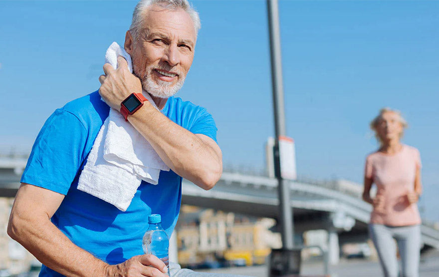 Senior man wiping sweat with towel after workout