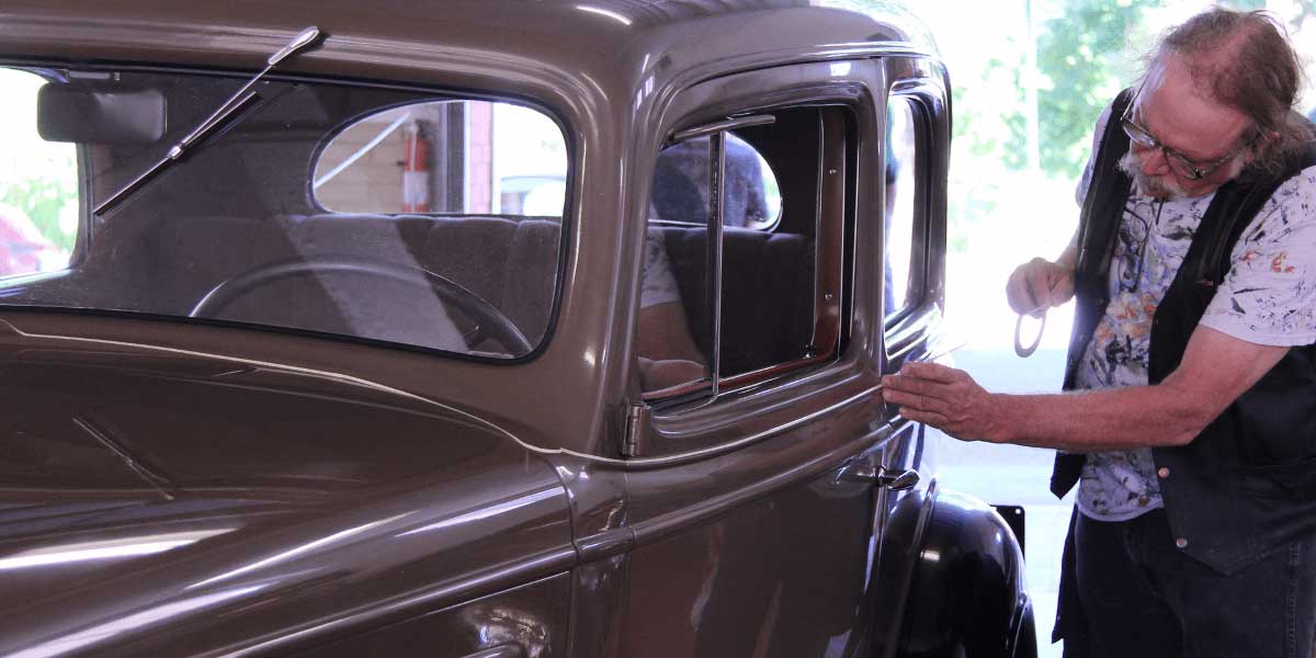 man touching up his restored car