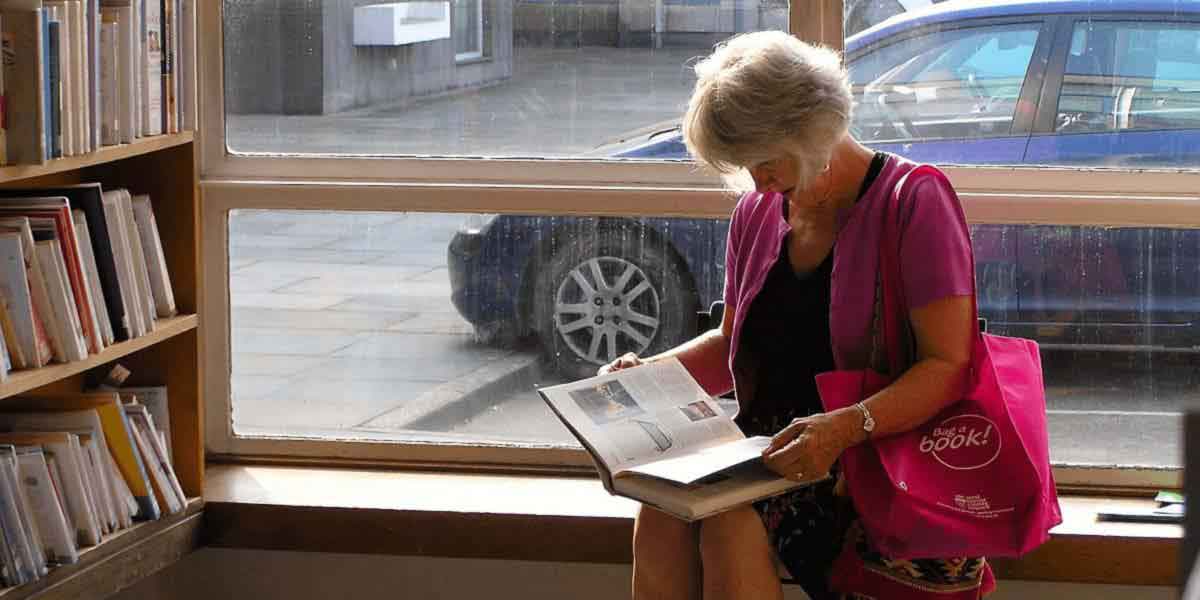 woman reading by window in library