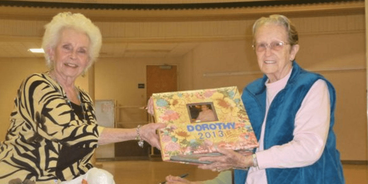 two women holding up scrapbook