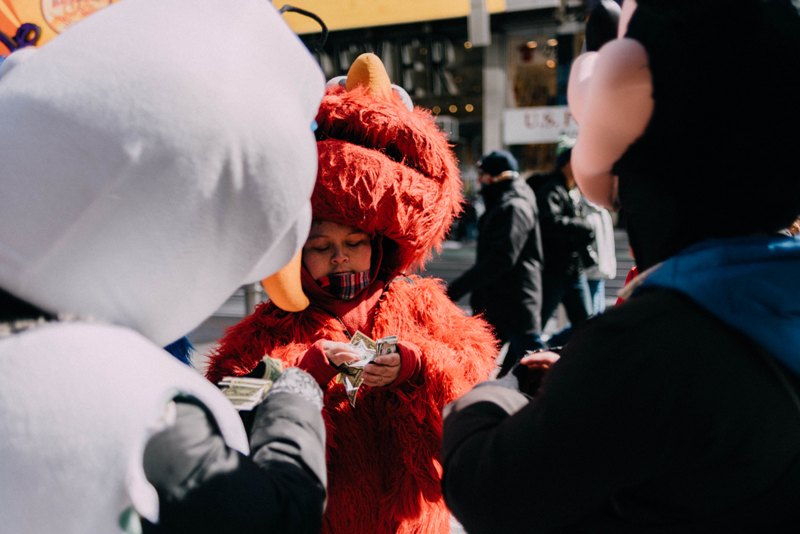 Little boy wearing Elmo costume counting money to buy tickets