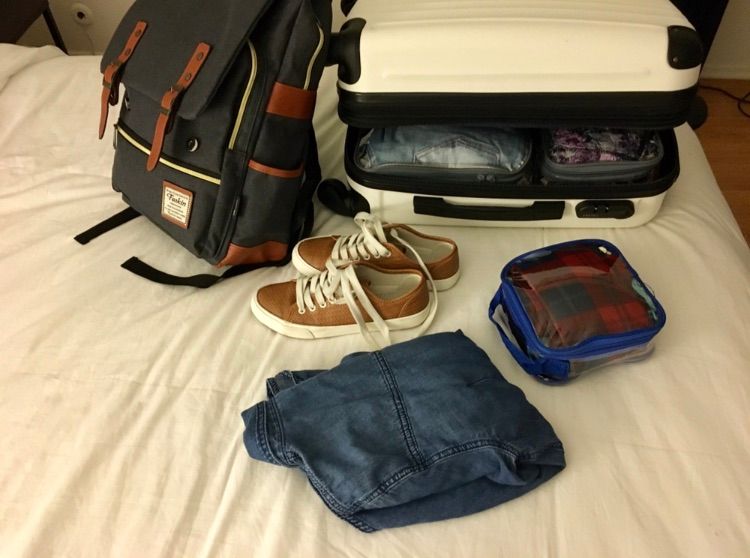 Travel essentials in suitcase and backpack