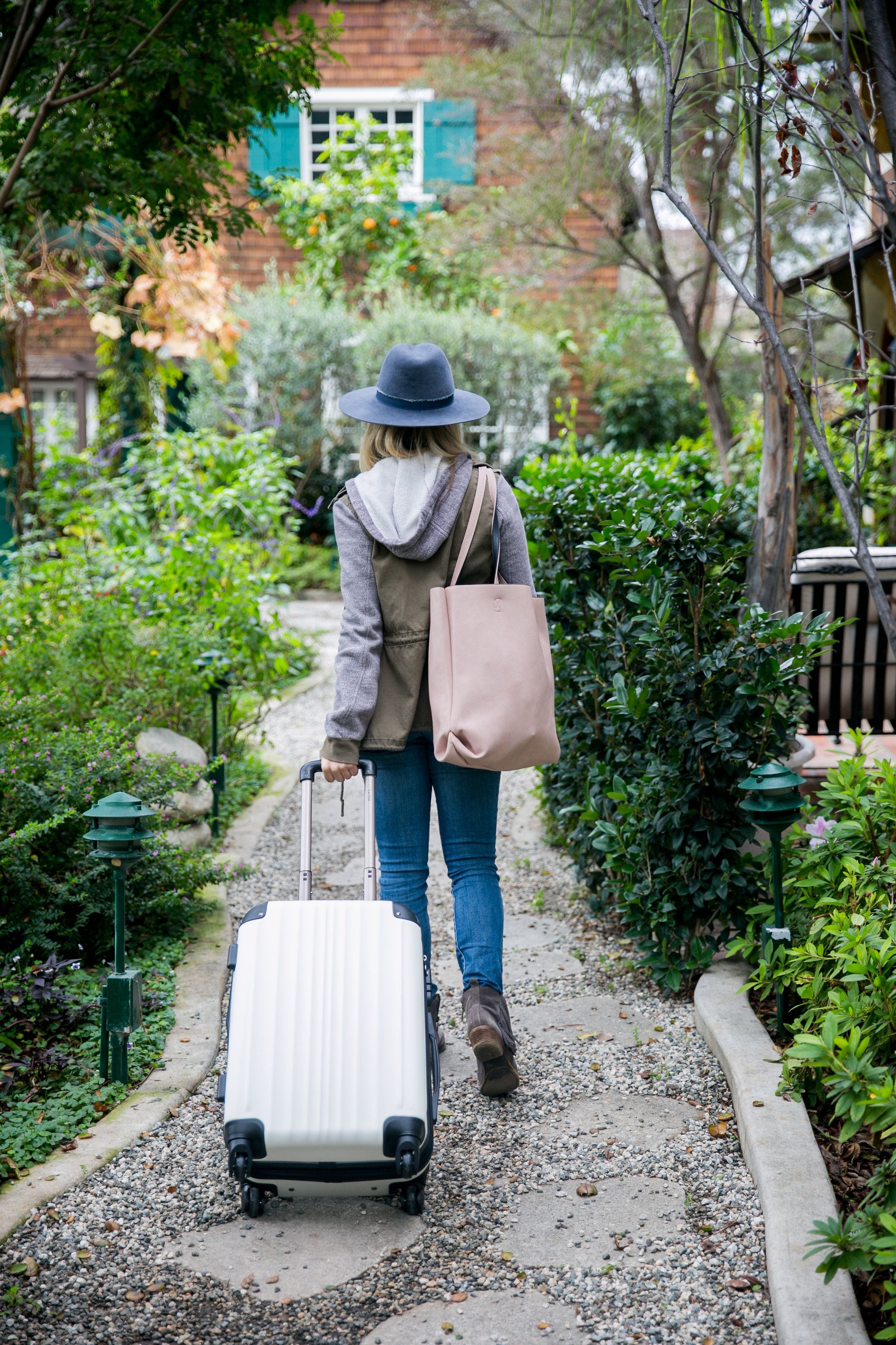 Woman walking carrying a tote bag and carry on suitcase