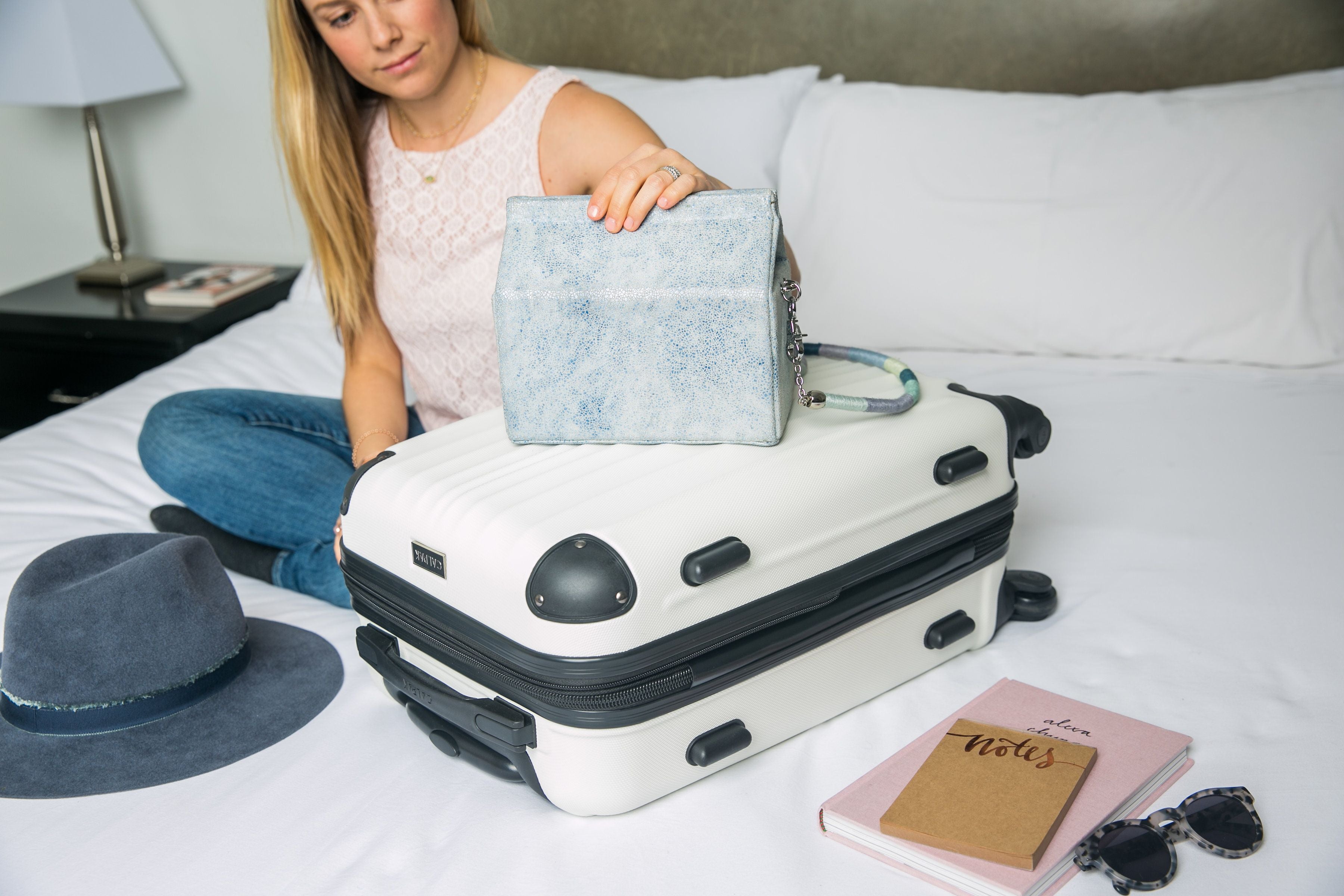 lady with her purse on a hard shell carryon suitcase