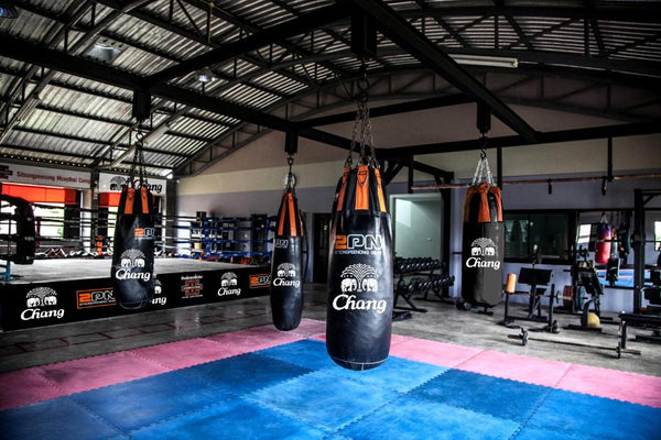 Indoor Muay Thai gym with fighting ring and punching bags and weights at sitsongpeenong. 