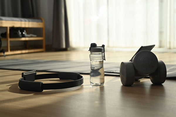 Workout anywhere. Dumbbells and bottle of water on wooden floor. Home exercising.