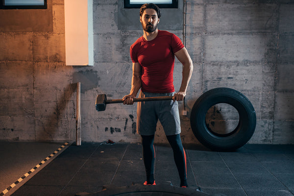 Male athlete ready to swing a hammer at the gym. 