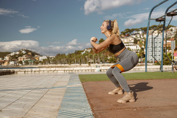 Shot of female athlete during morning exercise outdoors with resistance bands 