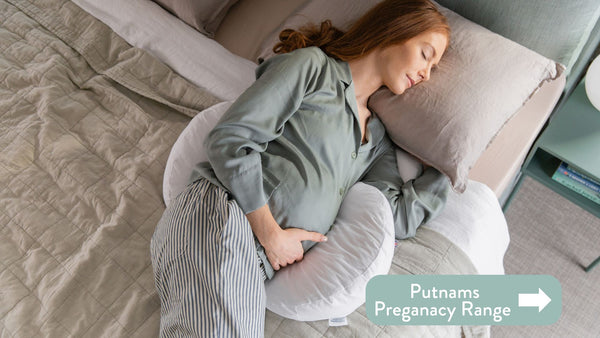 Person lying on bed with Putnams Pregnancy Cushion