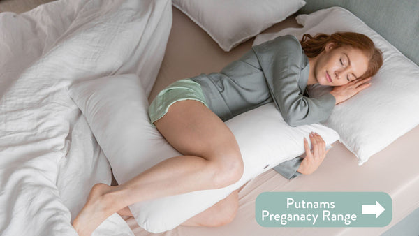 Person lying on a bed with putnams pregnacy pillow / cushion