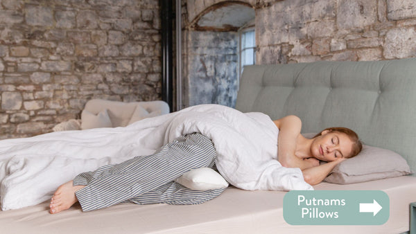 Person lying on their side in bed holding a pillow and sleeping