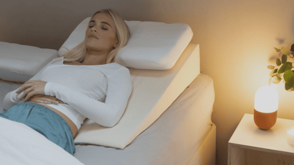 Person lying in bed on a Putnams bed wedge with a memory pillow