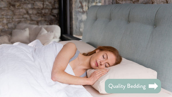 Person in bed with white sheets and a teal cushioned headboard