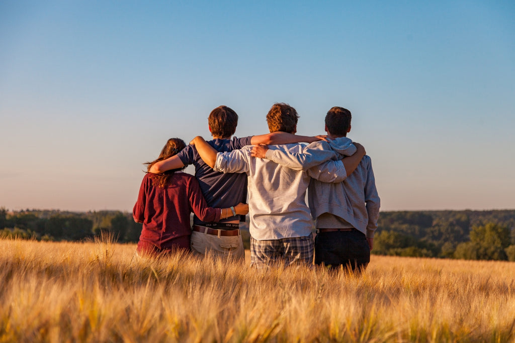 four friends with their arms around each other enjoying a wonderful vista