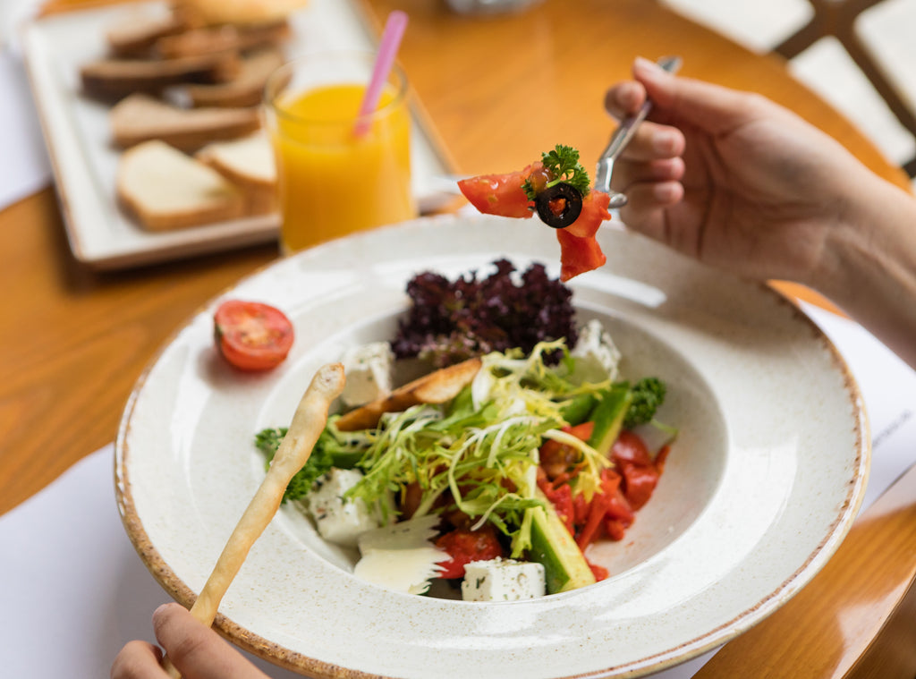 white plate on wooden table with healthy nutritious food including lettuce tomato cucumber and avocado