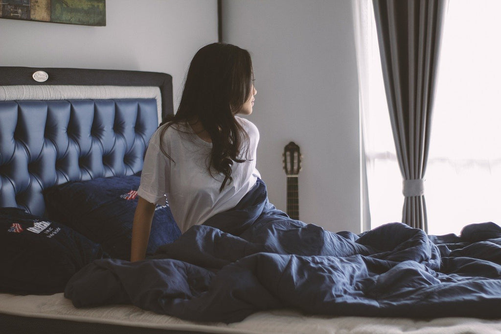 Person sitting up in bed looking out the window on a winter's morning