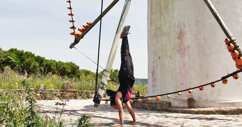 Myself next to a grain mill, doing a bodyweight handstand during my calisthenics training