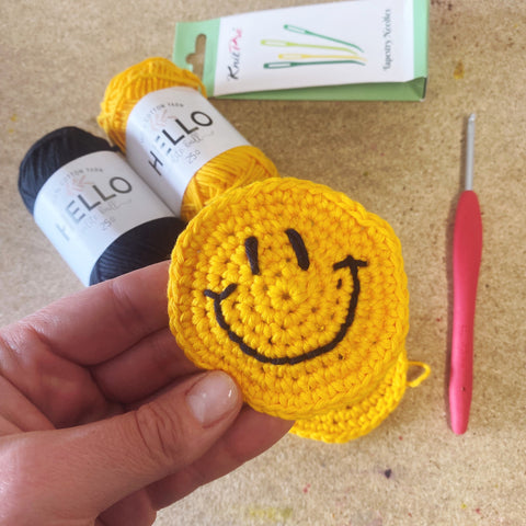 yellow smiley face crochet circle with embroidered face