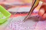 Close-up van het plaatsen van lila diamond painting steentjes met een pincet