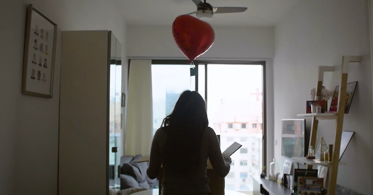 A woman opening a Better Than Flowers Package with a red heart shaped balloon flying out of it