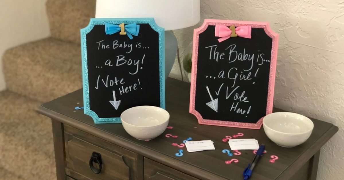 A pink and a blue chalkboard with two bowls and pieces of papers to vote for the gender of a baby in a gender reveal party