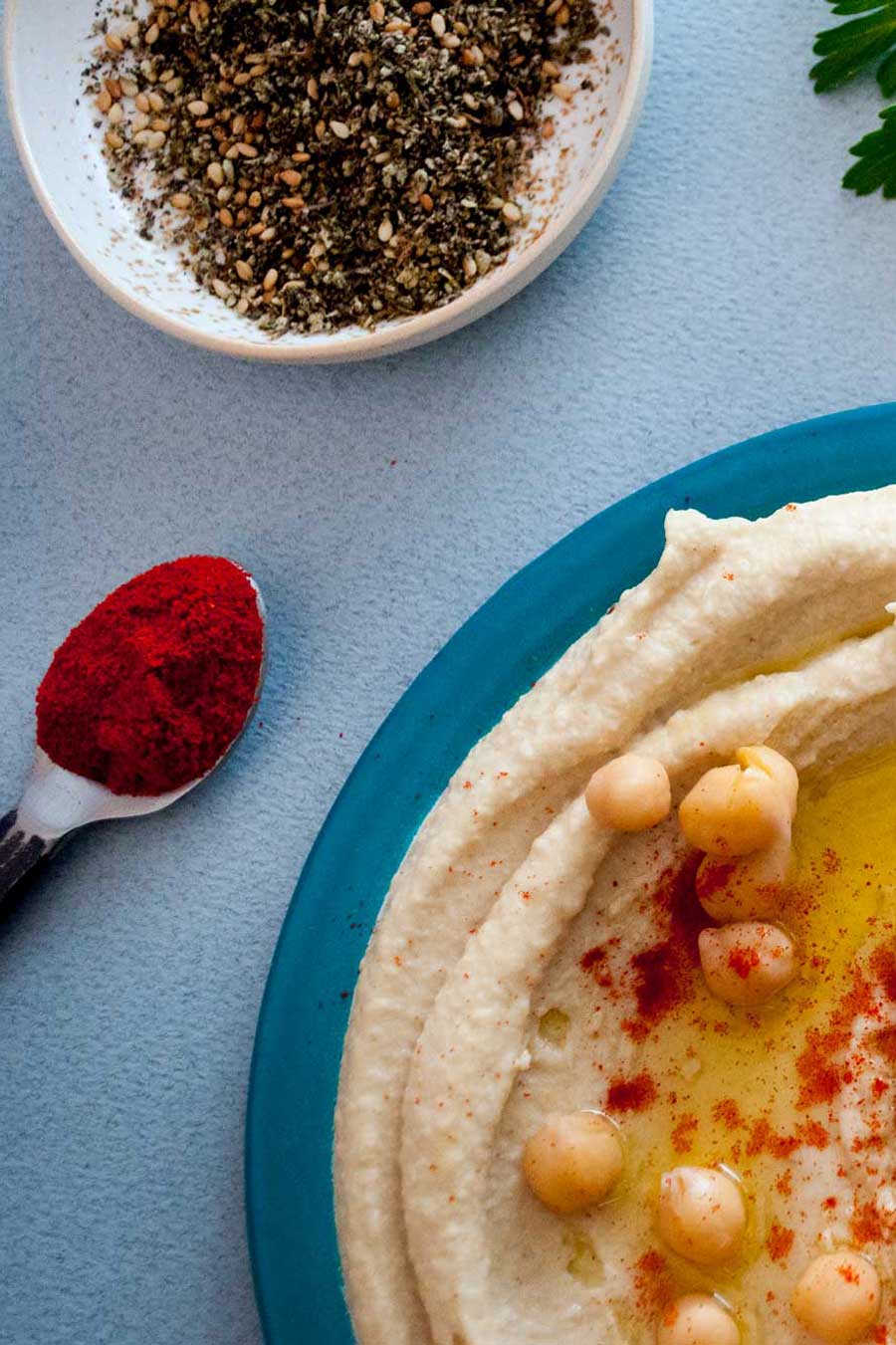 Assiette d'houmous avec du paprika biologique et une cuillère remplie de paprika à côté