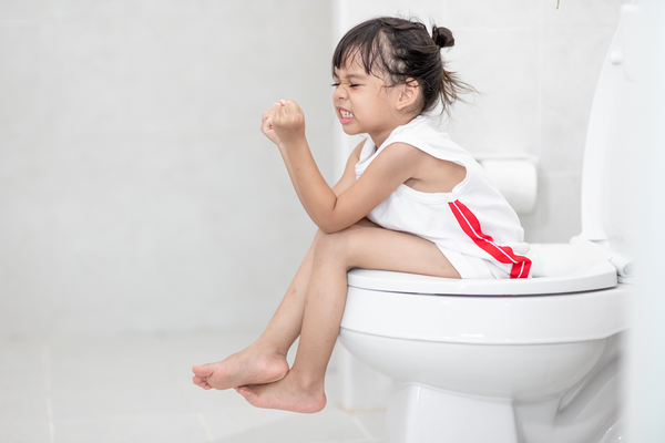 Kleines Mädchen sitzt pressend auf der Toilette. Sie leidet an hartem Stuhlgang und Verstopfung.