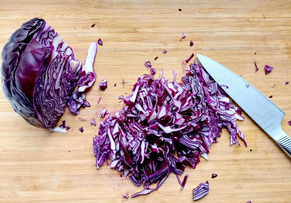 Rotkraut oder auch Rotkohl mit einem Messer zerkleinert auf einem Brett