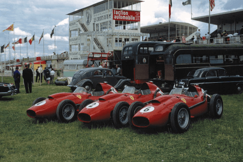 Three Ferrari 246 Grand Prix cars parked next to each other outside the racetrack